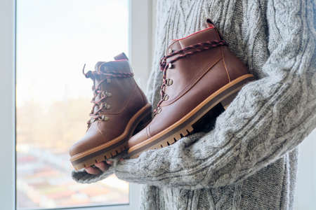 New womens leather brown waterproof hiking winter autumn boots in hands of female, trendy footwear for winter. Unpacking shoes, shopping online from home, shoe fashion storeの写真素材