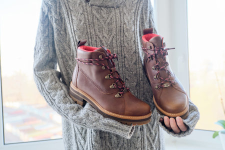 New womens leather brown waterproof hiking winter autumn boots in hands of female, trendy footwear...