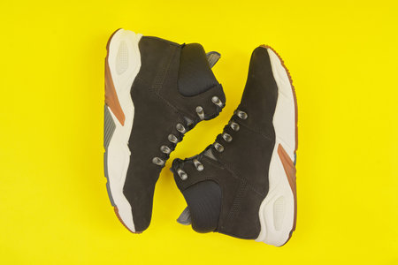 New womens leather black waterproof hiking winter autumn boots on yellow background, trendy footwear...