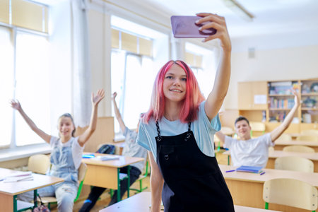 Teenagers students having fun in the classroom, bright trendy girl taking selfie photo with group of classmates friends at schoolの写真素材