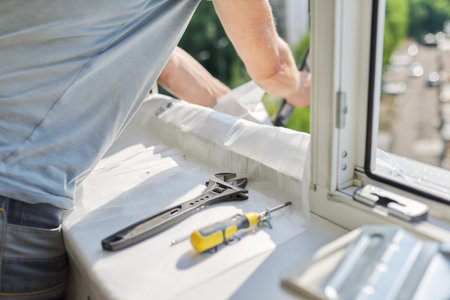 Installing an air conditioner in an apartment office, close-up of an engineer installers hands working with an outdoor unit, male technician repairing with toolsの写真素材