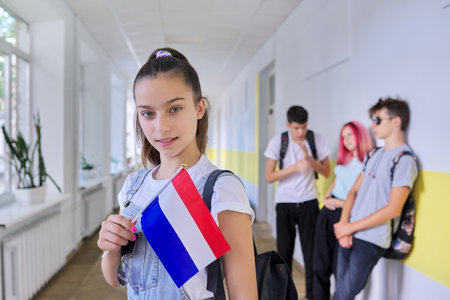 Student teenager girl with Netherlands flag inside school, school children group background. Europe, Netherlands, education and youth, patriotism people conceptの写真素材