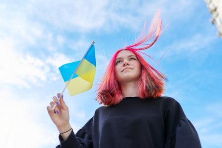 Female student teenager with Ukraine flag, blue sky with clouds background. Ukraine, education and youth, patriotism people conceptの写真素材