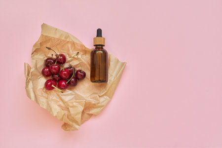 Natural healthy organic cosmetics, fruits, cherries, bottle with cosmetic product on pink background. Cosmetology, treatment, skincare, therapyの写真素材