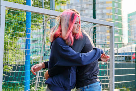 Teenagers guy and girl hugging at the meeting, sports city court backgroundの写真素材