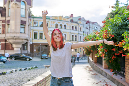Fashionable trendy happy teenage girl in headphones on the street of summer city.