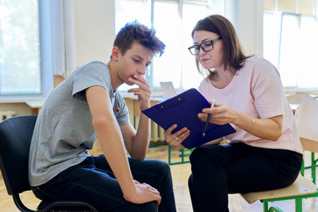 Woman school psychologist talking and helping student, male teenager. Mental health of adolescents,...