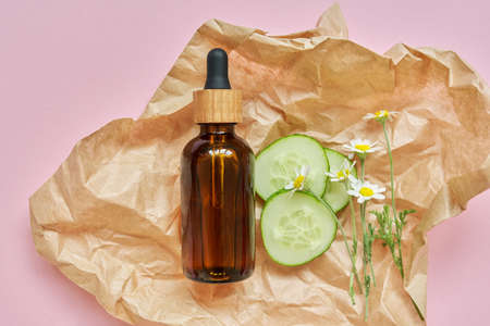 Medical organic herbal cosmetics, natural ingredients chamomile flowers cucumber, craft paper pink background, top viewの写真素材