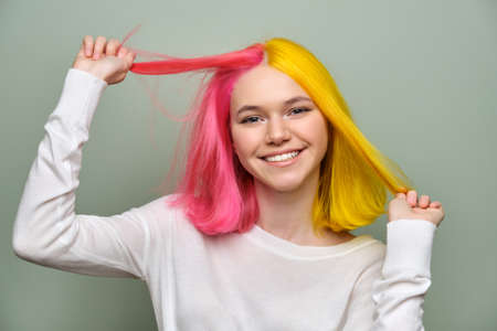 Dyed long hair close-up, girl fashion beauty model showing coloring on her hair, green studio background. Professional coloring, beauty, fashion, trendsの写真素材
