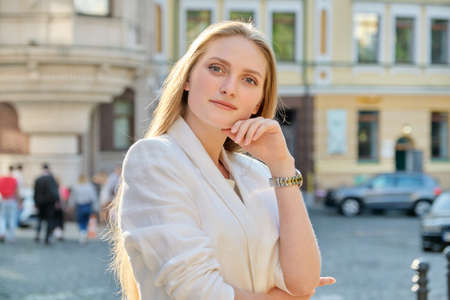 Outdoor portrait of young successful smiling business woman. Beautiful blonde female looking at the camera, city street backgroundの写真素材