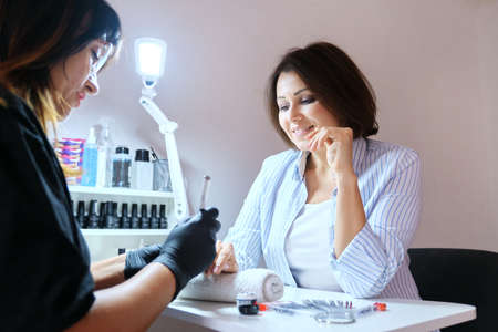 Middle aged woman in beauty salon doing manicure and hand care. Beauty, care, lifestyle of mature womenの写真素材