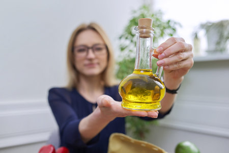 Olive oil in bottle in hand of woman nutritionist, healthy food, healthy lifestyle.