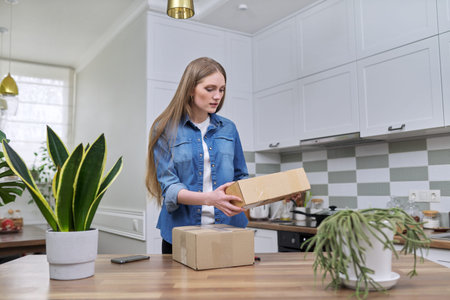 Young happy woman unpacking cardboard boxes, unboxing expected postal parcel with online shopping,...