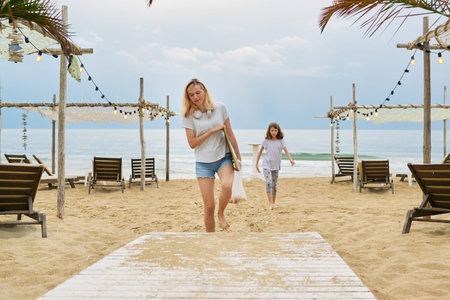 Two sisters teenage girls walking together with sea trip with watercolor paints drawing on an easelの写真素材