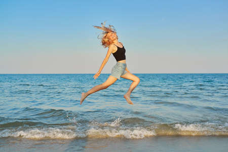 Young beautiful woman flying over the sea, happy female jumping over waterの写真素材