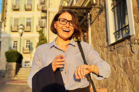 Mature successful business woman walking along city street.の写真素材