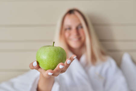 Close-up of a green ripe apple in a womans handの写真素材