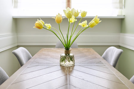 Vase with a bouquet of yellow tulips on a wooden tableの写真素材