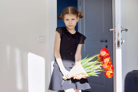 Mothers day, girl child with bouquet of red tulips flowers at homeの写真素材