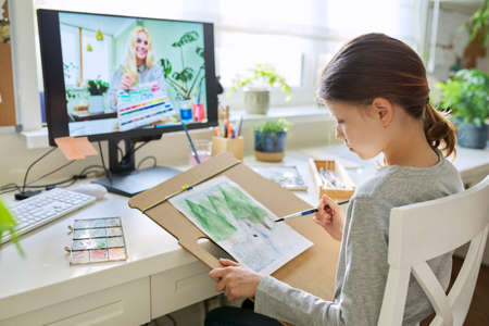 Online workshop on drawing. Girl child student painting with watercolors at homeの写真素材