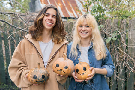 Couple of laughing teenagers with halloween pumpkins having funの写真素材