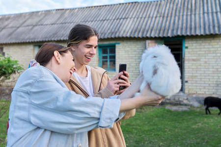 Mom and her teenage son laugh, photograph decorative rabbit on smartphoneの写真素材