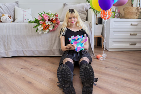 Birthday of teenage female. Hipster teenager at home with surprise gift in box