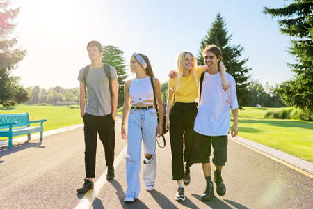 Outdoor, four teenagers walking together on roadの写真素材