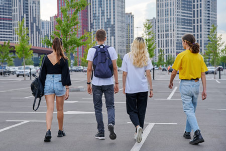 Group of teenagers walking together, back view, urban style, modern city background