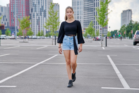 Running fashionable girl teenager, modern urban architecture parking background