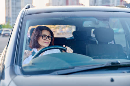 Middle-aged woman driver with glasses, female driving a car.の写真素材