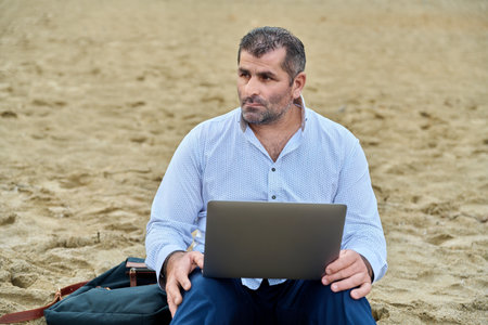 Serious confident mature man with laptop outdoorsの写真素材