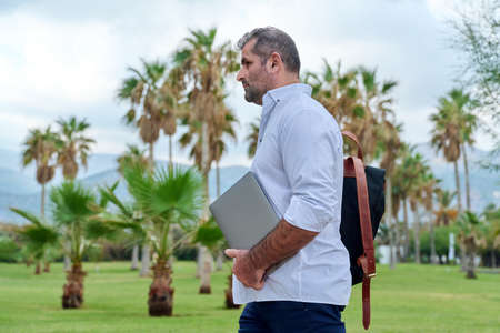 Portrait of serious confident mature man with laptop outdoorsの写真素材