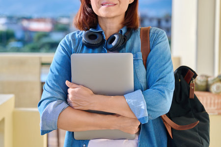 Portrait of a woman in wireless headphones with a laptop and a backpack