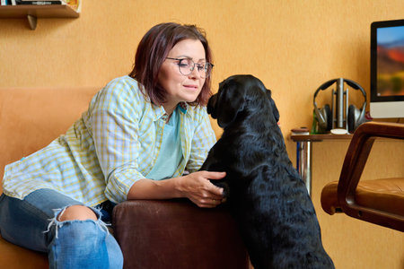 Middle-aged woman owner together with young dog at home