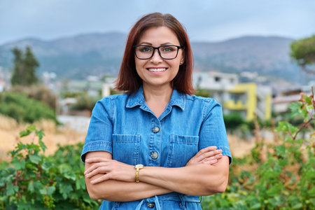 Outdoor portrait of smiling successful mature woman with folded hands.