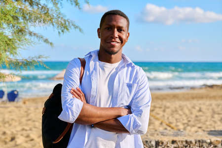Outdoor portrait of smiling confident man with folded hands, sea nature background.の写真素材