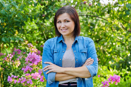 Portrait of smiling confident middle aged woman with crossed arms in gardenの写真素材