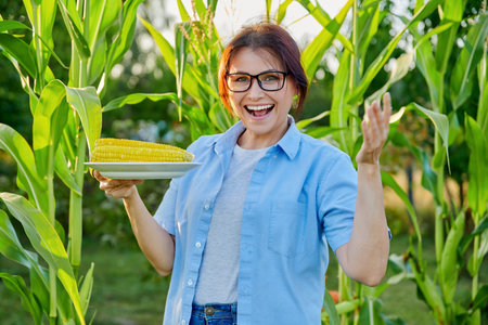 Middle-aged woman with boiled corn in plate