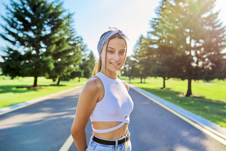 Outdoor portrait of a beautiful teenage smiling girl looking at the camera.