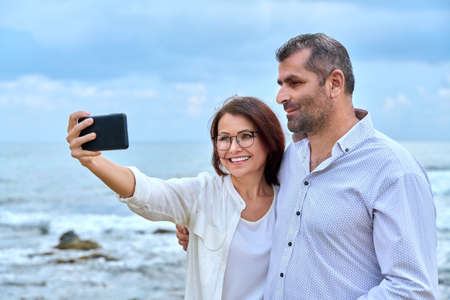 Happy mature couple taking selfie photo on smartphone.の写真素材