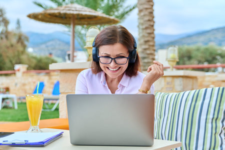 Woman with headphones looking at laptop, talking, using video call.