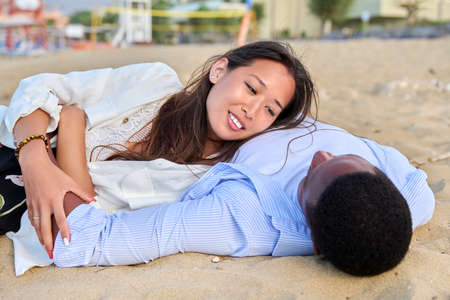 Young happy couple lying on the sand, top viewの写真素材