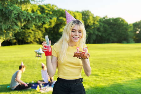 Beautiful teenage girl in a festiv hat on her birthday with a cake and candles.の写真素材