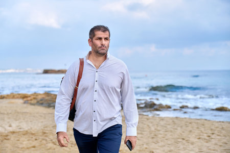 Outdoor portrait of mature man with backpack on the seashore.
