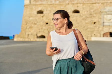 Outdoor portrait of smiling middle-aged woman walking through an old townの写真素材