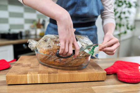 Close-up of a woman cutting a roasting sleeve with baked cooked chicken.の写真素材