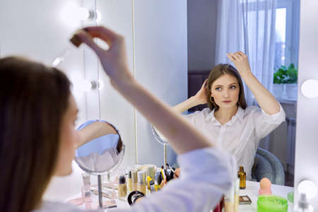 Young woman treating her hair using medical drops.の写真素材