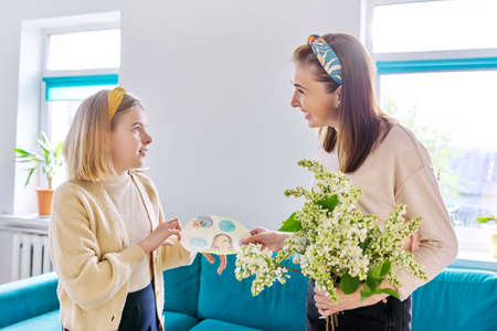 Happy mother and daughter child congratulating with bouquet of flowers and cardの写真素材