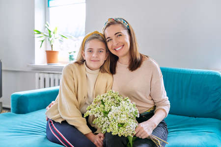 Happy mother and daughter child congratulating with bouquet of flowers and cardの写真素材